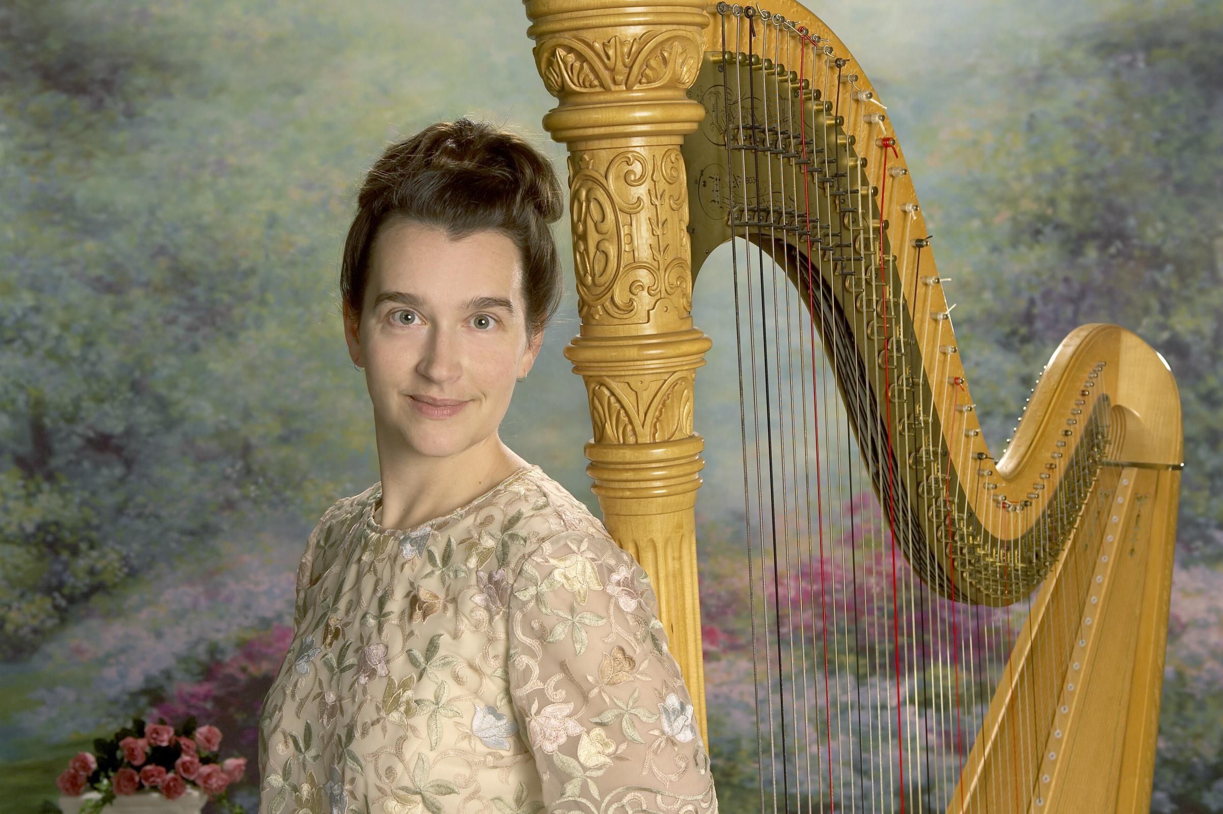Adrienne, Calgary harpist posing next to her Harp